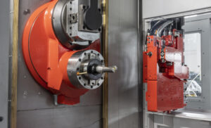 Two red metal parts with wires for CNC machining purposes on a machining center